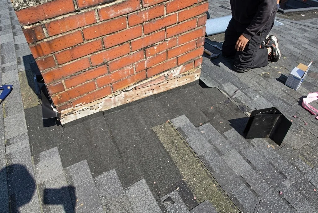 A SeaTac residential rooftop after repair showing replaced shingles and resealed flashing on a single-family home. The repaired section blends with the existing roof surface under overcast Pacific Northwest skies.